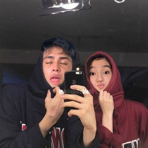 Two People Taking A Selfie In Front Of A Mirror With One Person Holding A Cell Phone