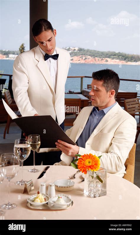 Man Ordering From The Menu To The Waiter In Restaurant Stock Photo