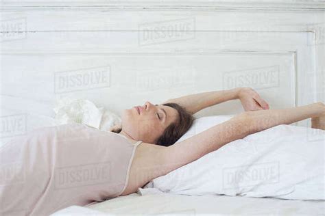 Woman Lying On Back In Bed Stretching Stock Photo Dissolve