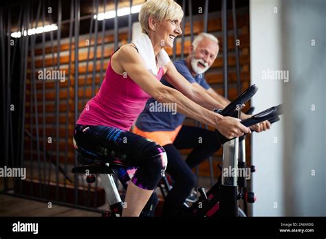Happy Fit Mature Woman And Man Cycling On Exercise Bikes To Stay Healthy Stock Photo Alamy