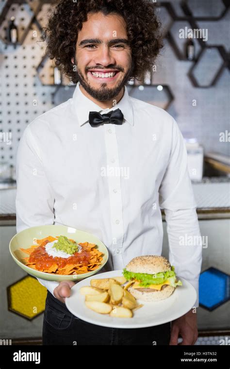Waiter Holding Plates Of Snacks And Burger In Bar Stock Photo Alamy