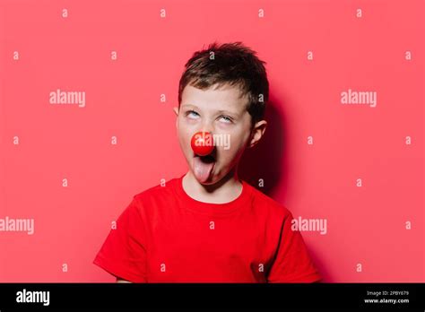 Portrait Of Humorous Kid Making Funny Face With Red Nose While Looking