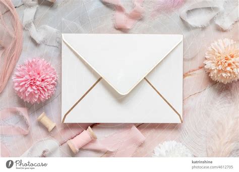 White Envelope Between Pastel Flowers Silk Ribbons And Feathers On