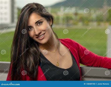 Belle Brune Et Longue Fille De Cheveux Avec Un Cardigan Rouge Souriant à La Caméra Photo Stock