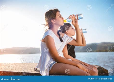two girls drinking water and sitting on dock stock image image of outdoors cold 75164155