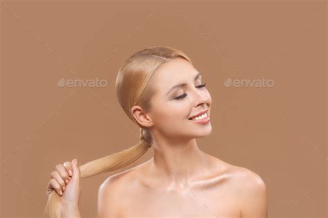 beautiful nude blonde woman with long hair and closed eyes isolated on brown haircare concept