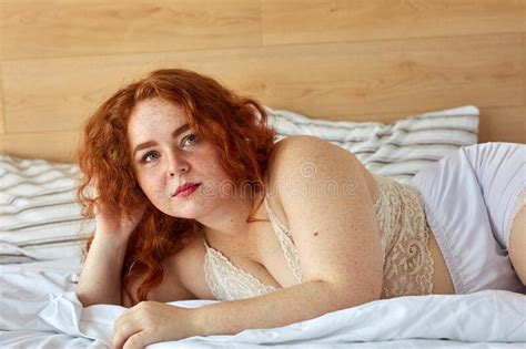 Red Haired Chubby Woman In Lingerie Lies On Bed Have Rest Stock Image
