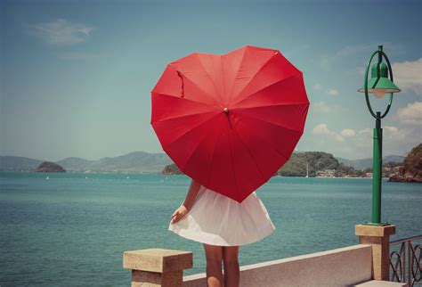 Woman Wearing White Dress Holding Red Heart Shape Umbrella Standing In