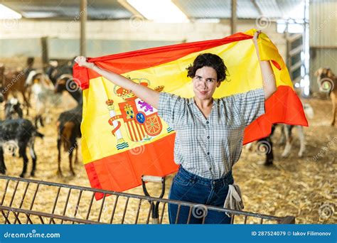 Happy Female Farmer Standing In Goat Shed With Spanish Flag Stock Image
