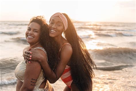 two african american female friends swimming and laughing at the beach by stocksy contributor