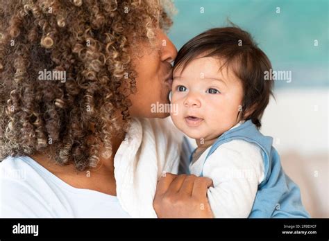 Mother Kissing Cute Baby On Forehead At Home Stock Photo Alamy