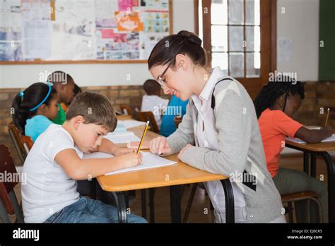 Pretty Teacher Helping Pupil In Classroom Stock Photo Alamy