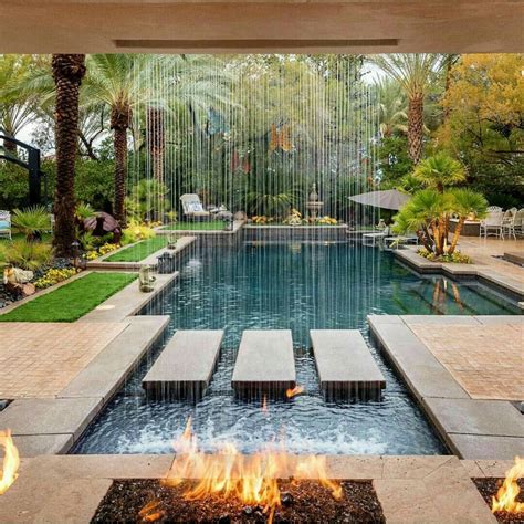 A Fire Pit In The Middle Of A Pool Surrounded By Palm Trees