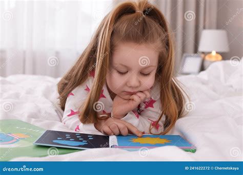 Cute Little Girl Reading Book On Bed At Home Stock Photo Image Of