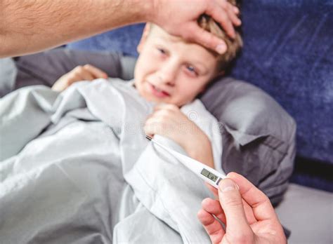 Father Checks The Temperature Of His Son Who Has Stock Image Image Of
