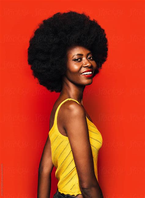 Happy Afro Woman Posing Over Red Background By Stocksy Contributor Victor Torres Stocksy