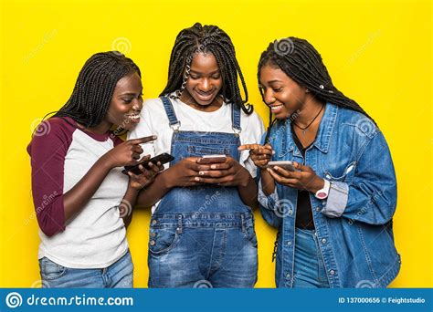 Three Beautiful Happy African Women Communicating And Using Smartphones