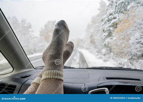 Female Feet In Woolen Socks On The Dashboard Of A Car In Winter