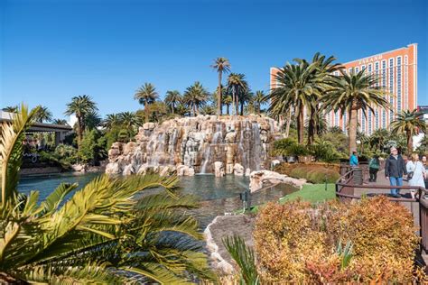 An Artificial Waterfall And Pool With Palm Trees Next To The Mirage
