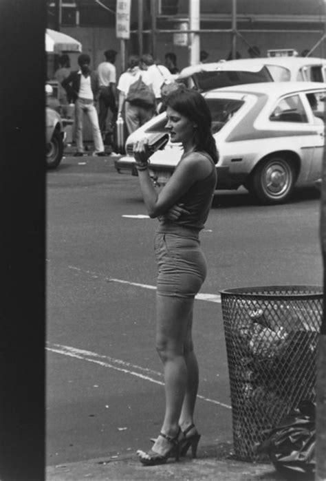 A Woman Is Standing On The Side Walk Talking On Her Cell Phone While Holding A Baseball Bat