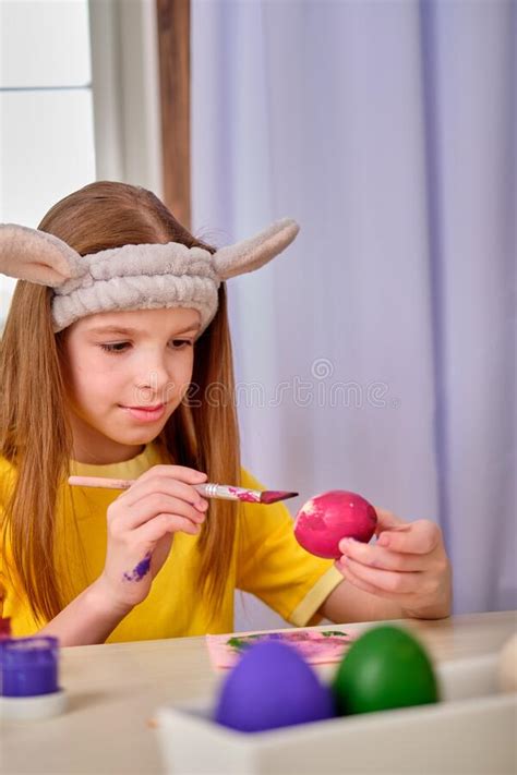 A Girl Paints Easter Eggs With Paints Portrait Of Caucasian Girl