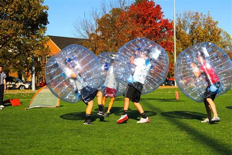 Three People Are Playing With Inflatable Balls On The Grass