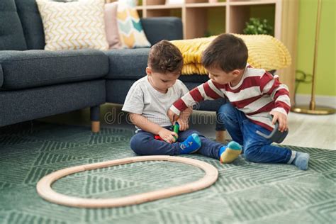Two Kids Playing With Train Toy Sitting On Floor At Home Stock Image