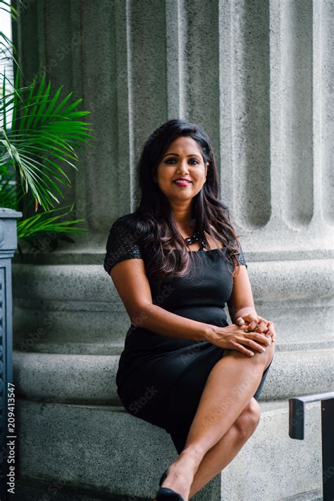 Portrait Of A Youthful But Confident And Mature Indian Woman Sitting And Leaning On A Concrete