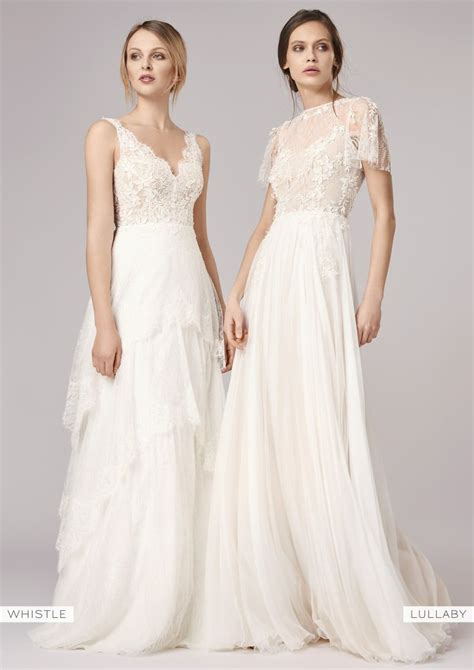 Two Women In Wedding Gowns Standing Next To Each Other With Their Hands On Their Hips