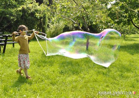 Girl Making Giant Bubbles Using Home Made Bubble Mix Recipe And Wands
