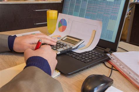 Corporate Businessman Working At Office Desk He Is Using A Calculator