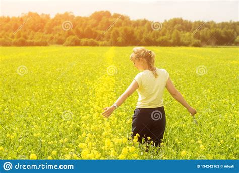 Happy Young Woman Enjoying Summer And Nature In Yellow Flower Field