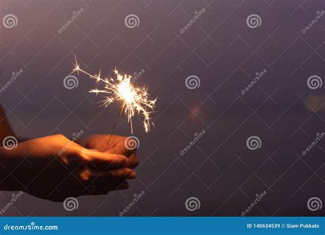 happy cute girl holding a sparkler on beach during sunset celebration concept stock image