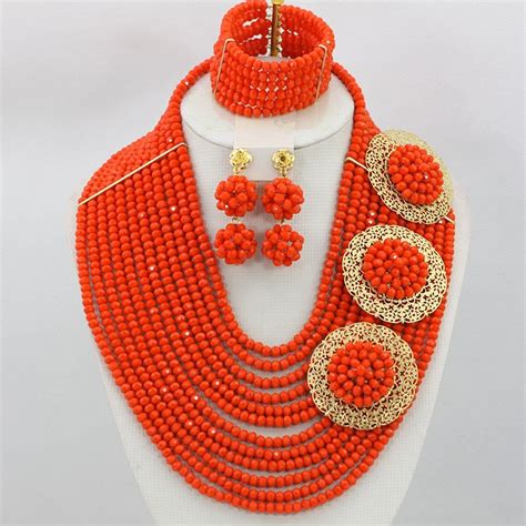 An Orange Beaded Necklace And Earring Set With Matching Earrings On A