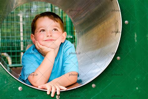 عکس با کیفیت پسر بچه دراز کشیده در یک تونل در حال فکر کردن و رویا پردازی عکس با کیفیت و تصاویر