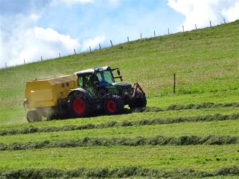 Tractor Mowing Grass On A Sloping Meadow In Midsummer Stock Photo