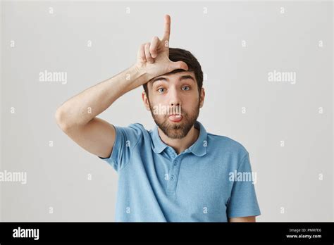 Portrait Of Cute Bearded Caucasian Guy Sticking Out Tongue And Holding