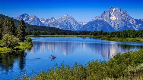 Boat On River In Grand Teton National Park With Landscape Of Mountains