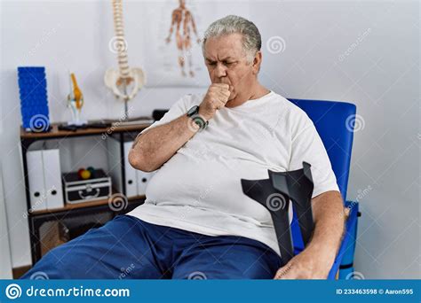 Senior Caucasian Man At Physiotherapy Clinic Holding Crutches Feeling