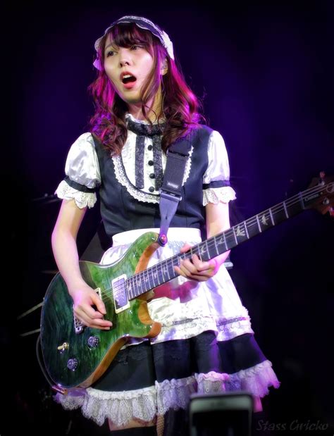 A Woman In A Dress Holding A Green Guitar