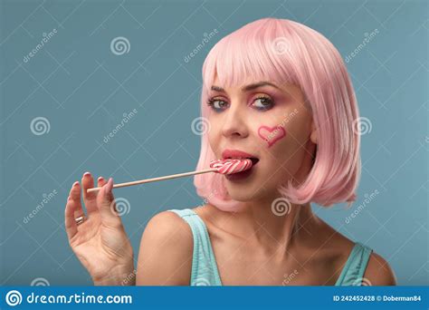 close up of a flirtatious female model on blue background wearing a pink wig holding different