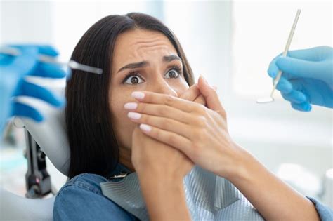 cliente do sexo feminino cobrindo a boca com as mãos sentada na cadeira odontológica foto premium