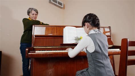 Music Lesson Girl Playing Piano Elder Teacher Stands Near The Piano