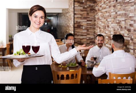 Cheerful Female Waiter Welcoming Guests To Country Restaurant Stock
