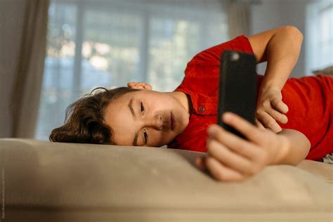 Boy Watching Videos On Mobile Phone By Stocksy Contributor Dejan