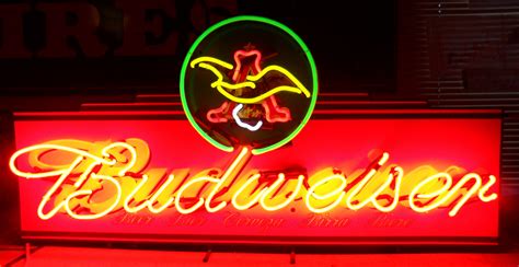 The Budweiser Neon Sign Is Lit Up In Red Yellow And Green Colors