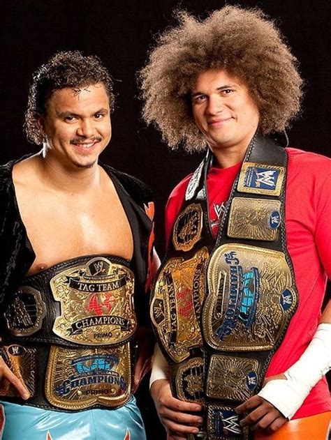 Two Men Standing Next To Each Other Wearing Wrestling Belts