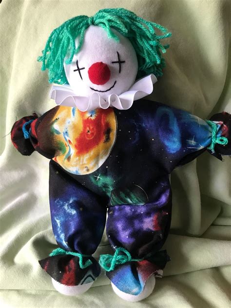 a creepy clown doll with green hair on a white sheet