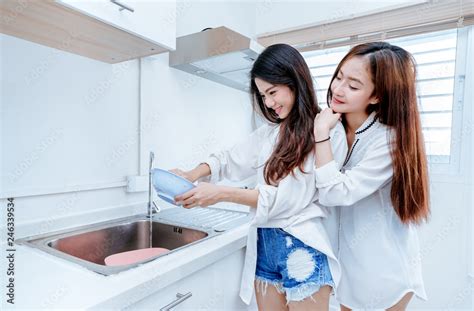 same sex asian lesbian couple women asian doing housework or chores helping with washing dishs
