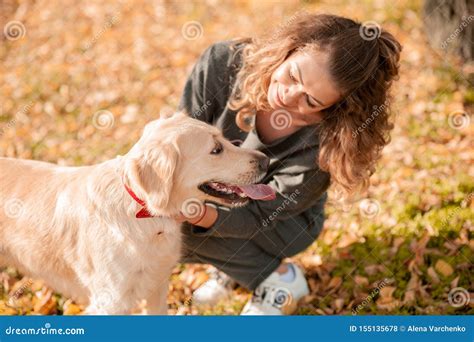 Closeup Of Curly Woman Sitting With Her Dog In Autumn Leaves Outdoors